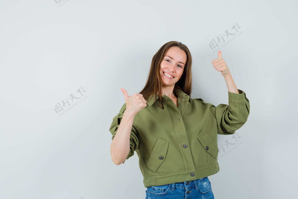 双人穿着绿色夹克和短裤的年轻女士向上竖起大拇指 看上去很高兴正面图拇指积极深色