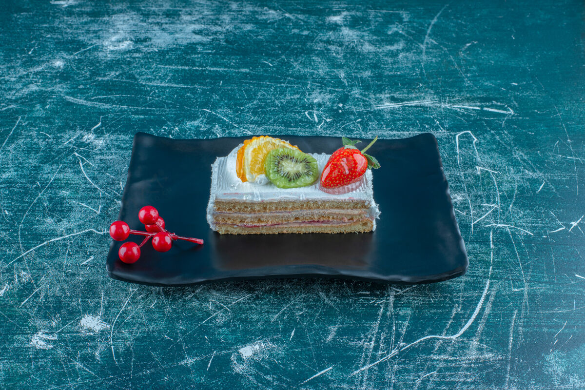 拼盘在蓝色背景的盘子上放上水果馅的蛋糕片高质量的照片草莓顶部美味