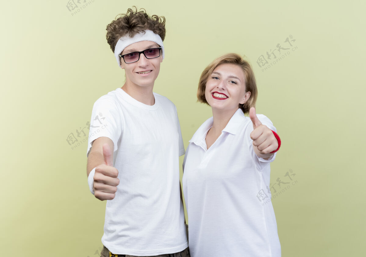 拇指一对年轻的运动男女站在轻墙上 快乐而积极地竖起大拇指运动立场光