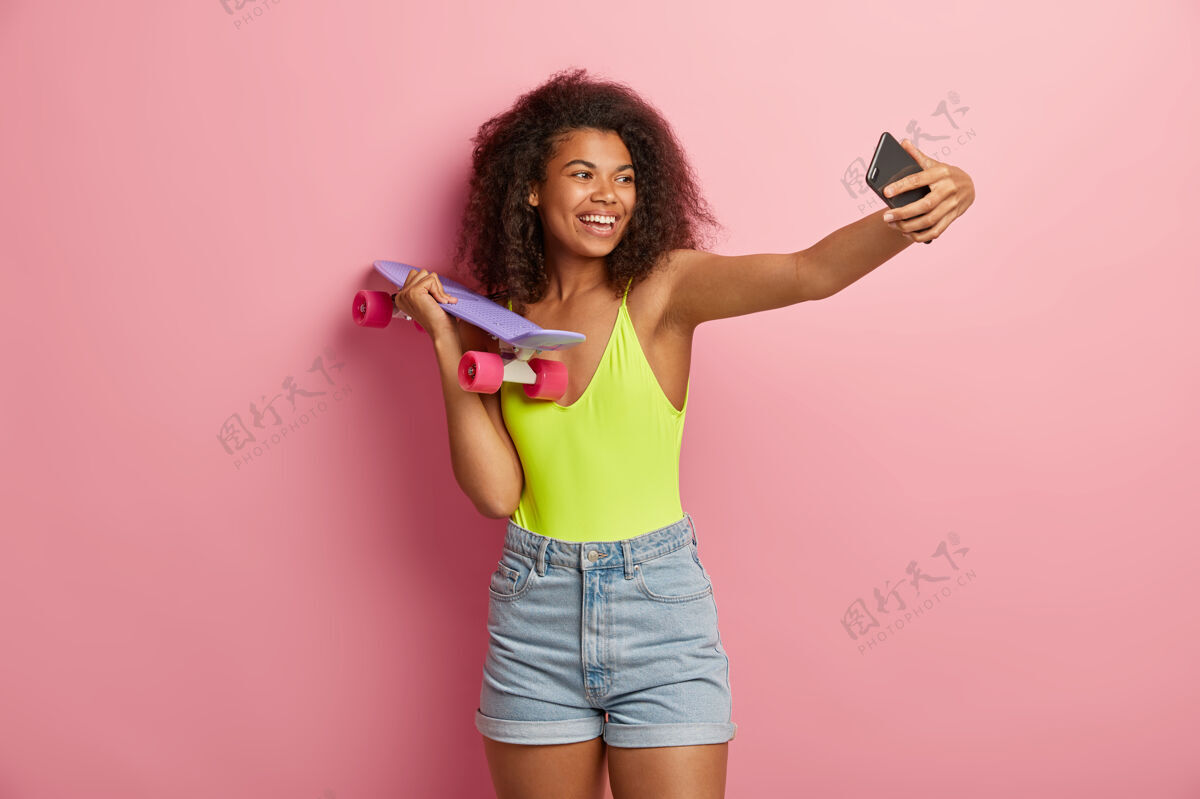 手机快乐的运动女性与滑板合影肖像爱好溜冰