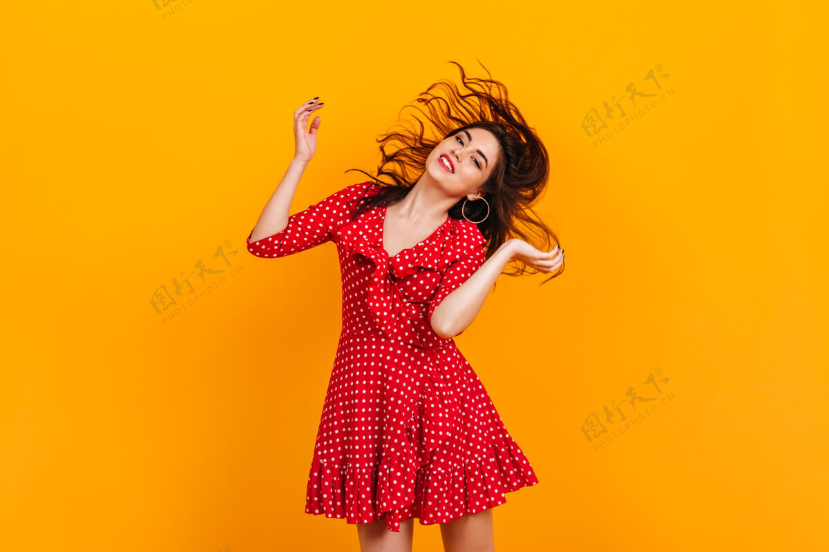 棕色头发穿着红色短裙的时髦女孩在玩头发黄色墙上戴着耳环的黑发女郎的肖像人类女孩女人