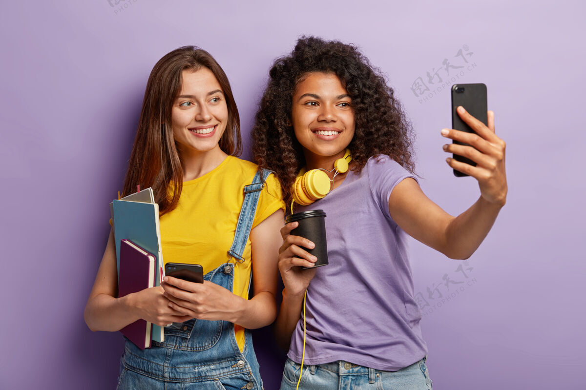 电话快乐的女朋友们拿着手机摆姿势课本青少年女孩