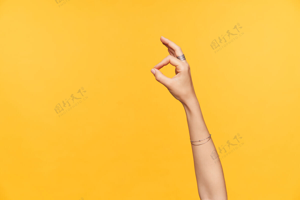 语言室内照片 精心打扮 皮肤白皙的女性手与饰物被提出 而显示ok手势与手指 隔离在黄色背景白皙特写附件