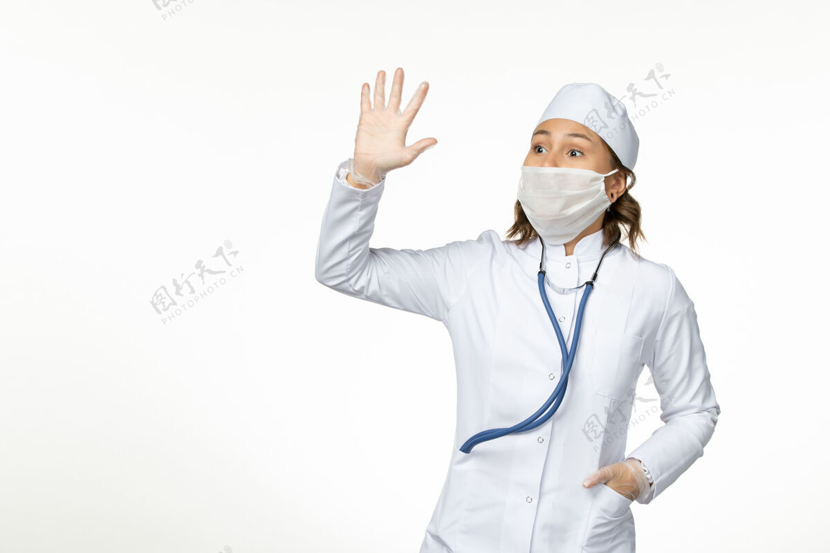 到期正面图年轻女医生戴防护无菌口罩因冠状病毒在白色表面挥舞病毒冠状病毒灭菌