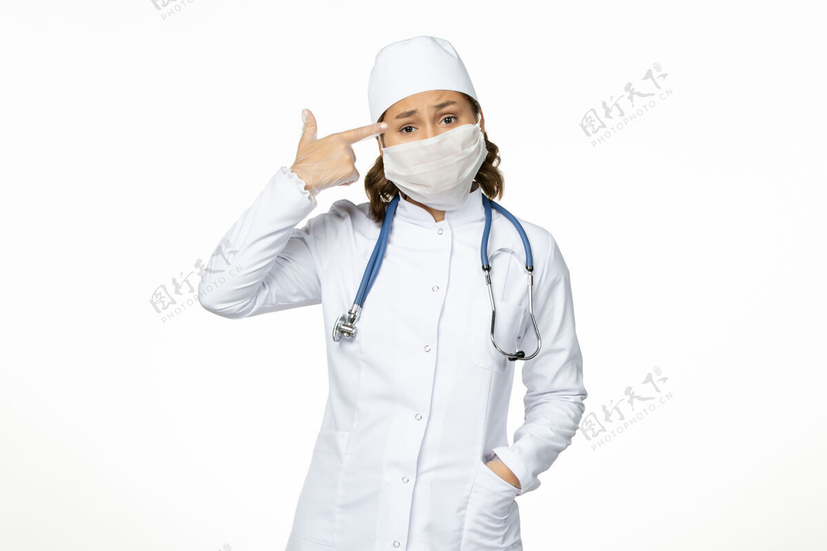 西装前视图年轻的女医生穿着白色的医疗服 戴着口罩 因为白色的地板上有冠状病毒口罩专业疾病