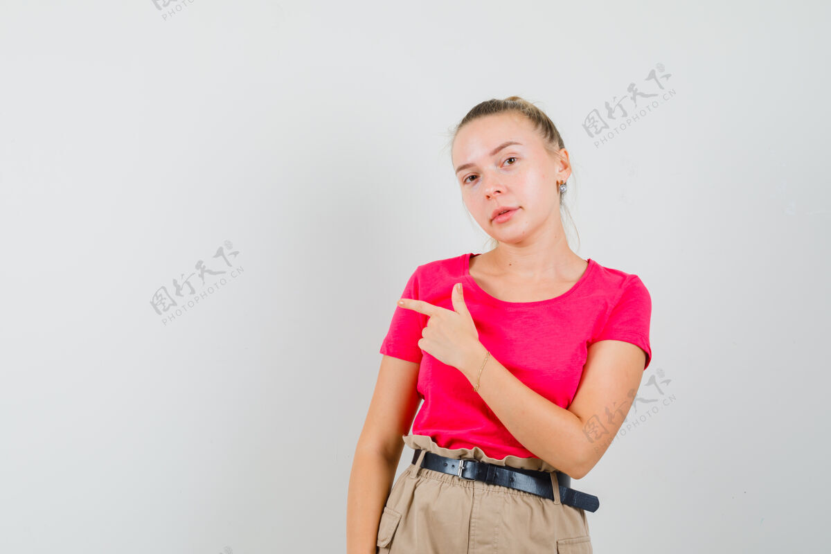时尚一个穿着t恤和裤子的年轻女人指着旁边 看起来很懂事人裤子成人