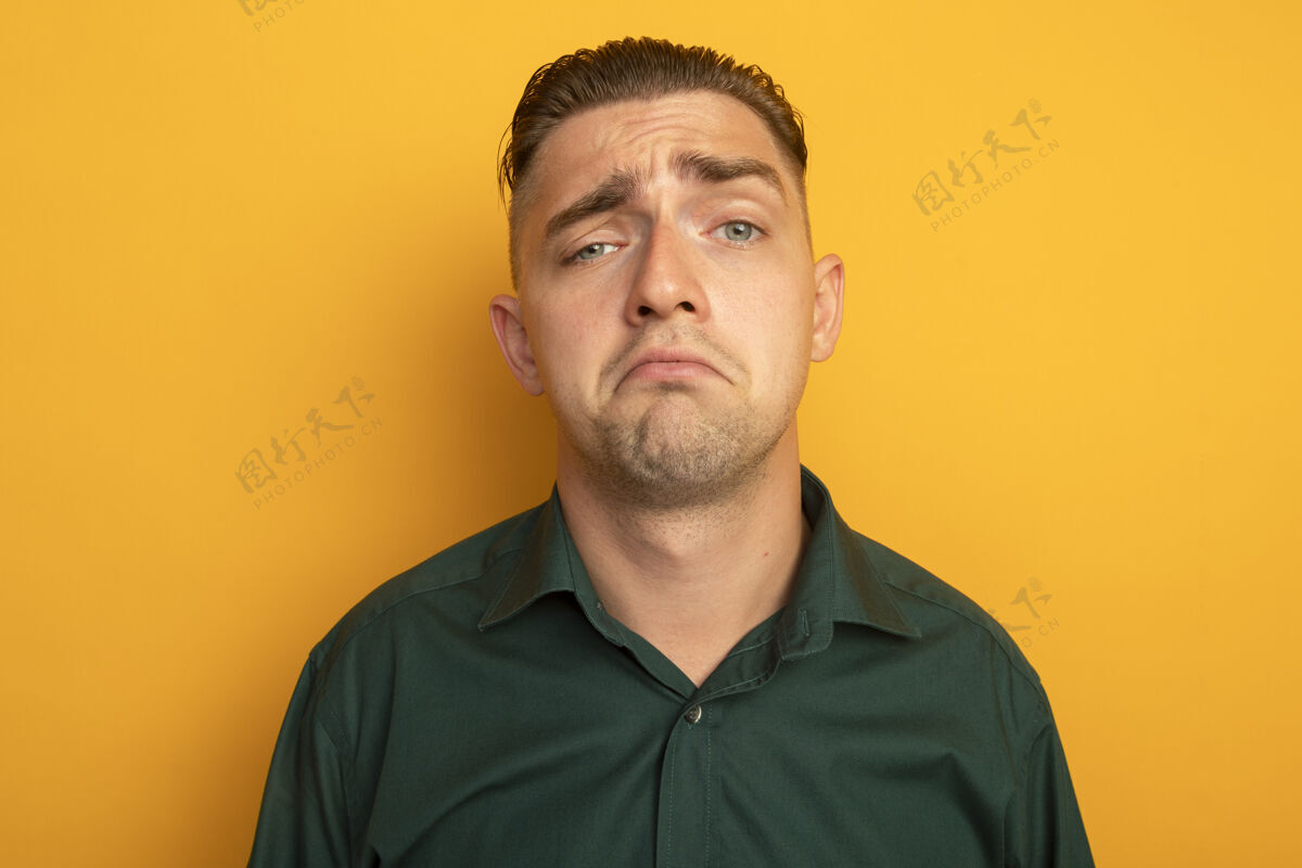 橙色不快乐的年轻帅哥穿着绿色衬衫 表情悲伤表情帅气表情