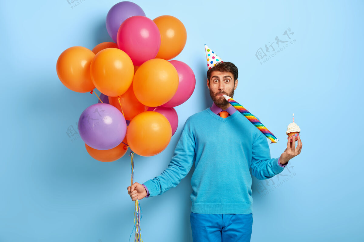 节日戴着生日帽 戴着气球 穿着蓝色毛衣的滑稽家伙休闲五颜六色裤子