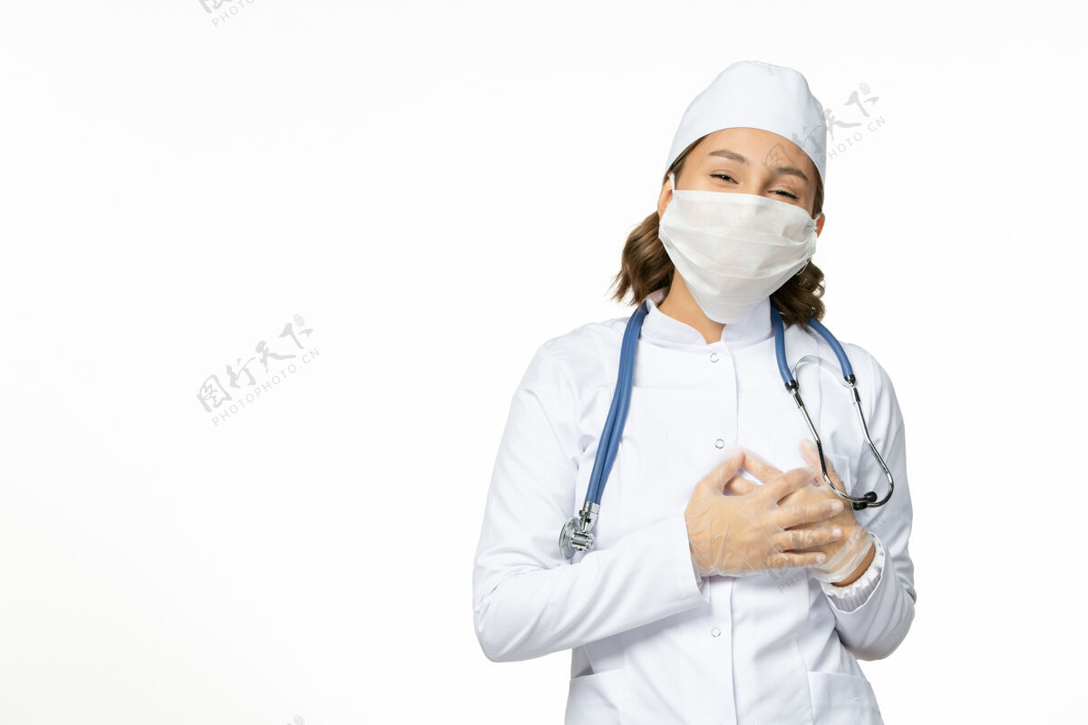 医疗正面图年轻女医生带着无菌口罩和手套由于冠状病毒在浅白的表面病毒面罩医疗器械