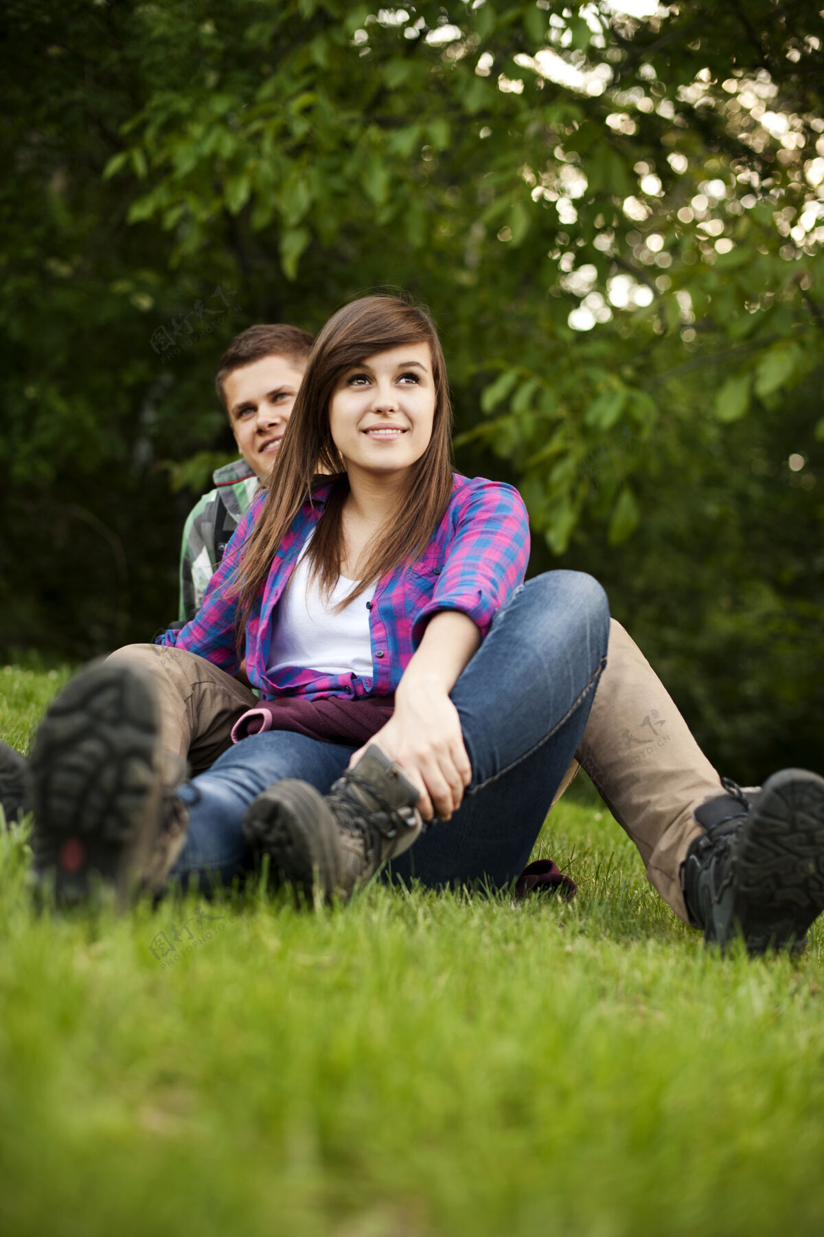 鞋子坐在空地上的年轻夫妇草地徒步旅行旅游