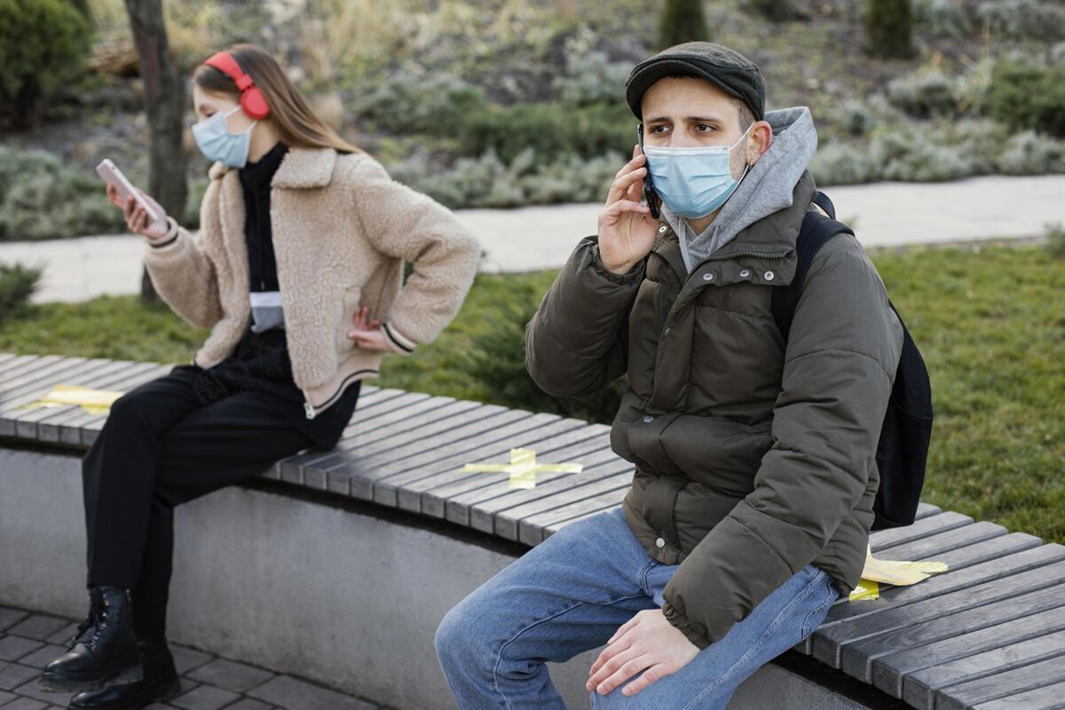 社会距离坐在远处戴着面具的人外科口罩设备女人