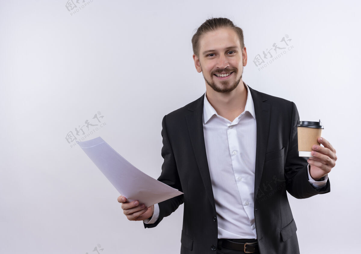 站着穿着西装的帅哥拿着咖啡杯和空白的书页看着相机 站在白色的背景上开心地微笑着微笑白色空白