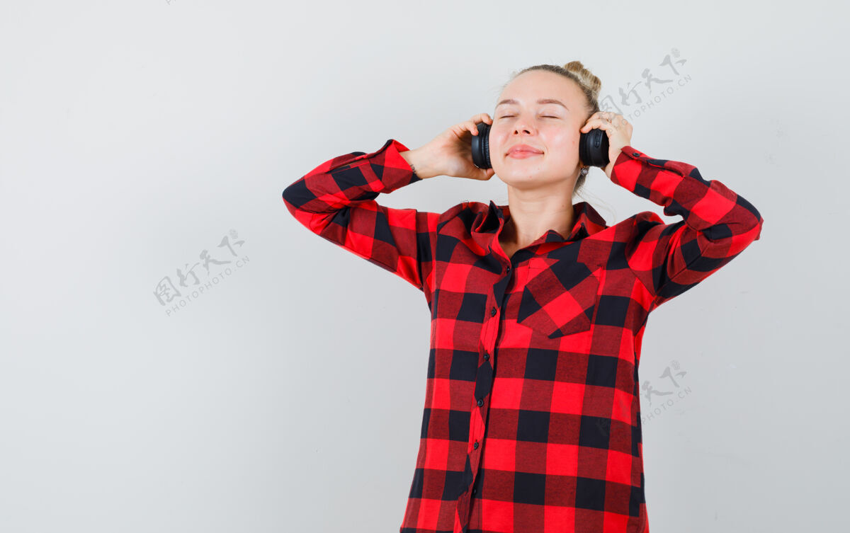 人穿着格子衬衫戴着耳机听音乐的年轻女性 看上去很高兴正视图人可爱美丽