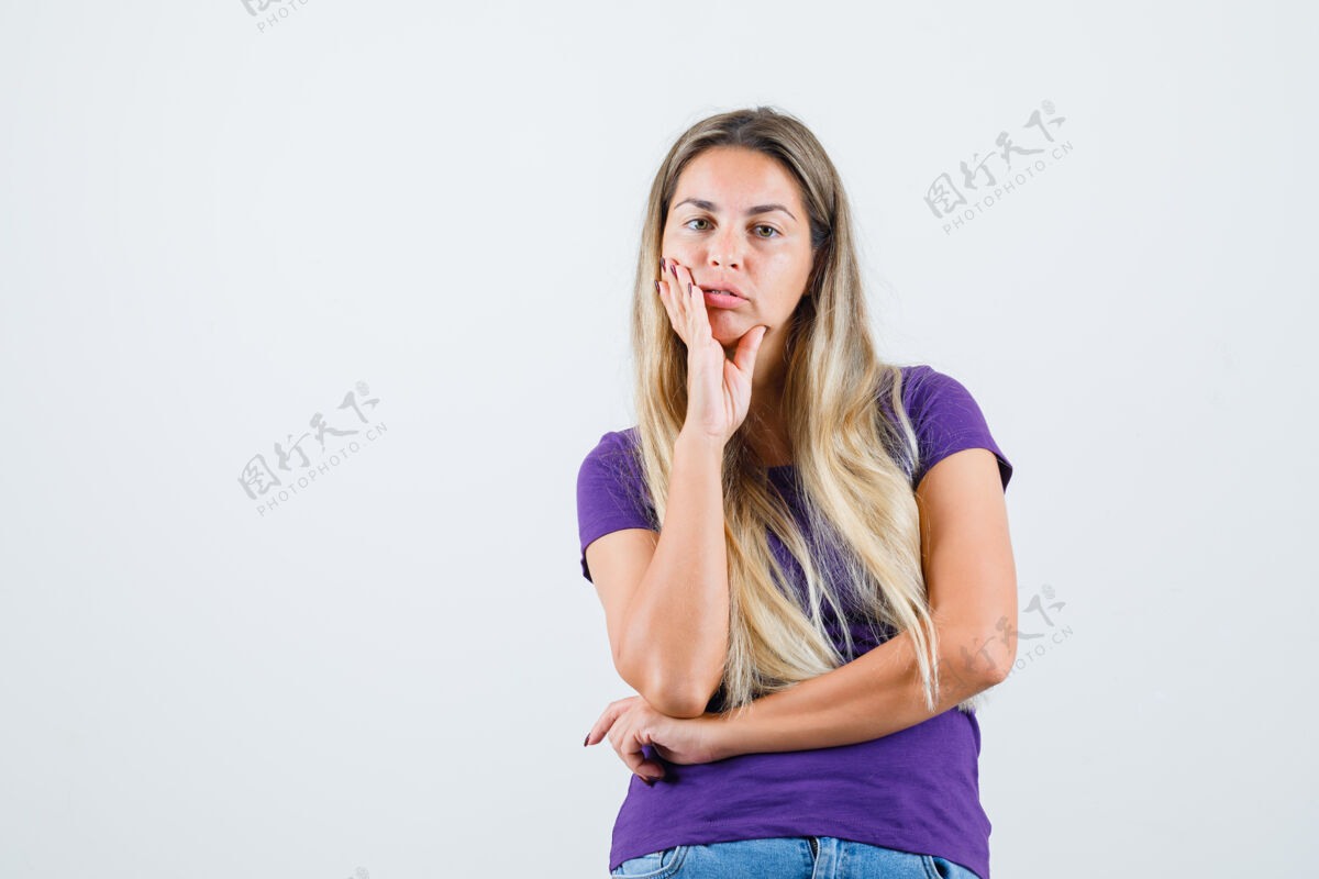美丽年轻的女士穿着紫色的t恤 牛仔裤站在倾听的姿势 看起来很理智前视图一起看时尚