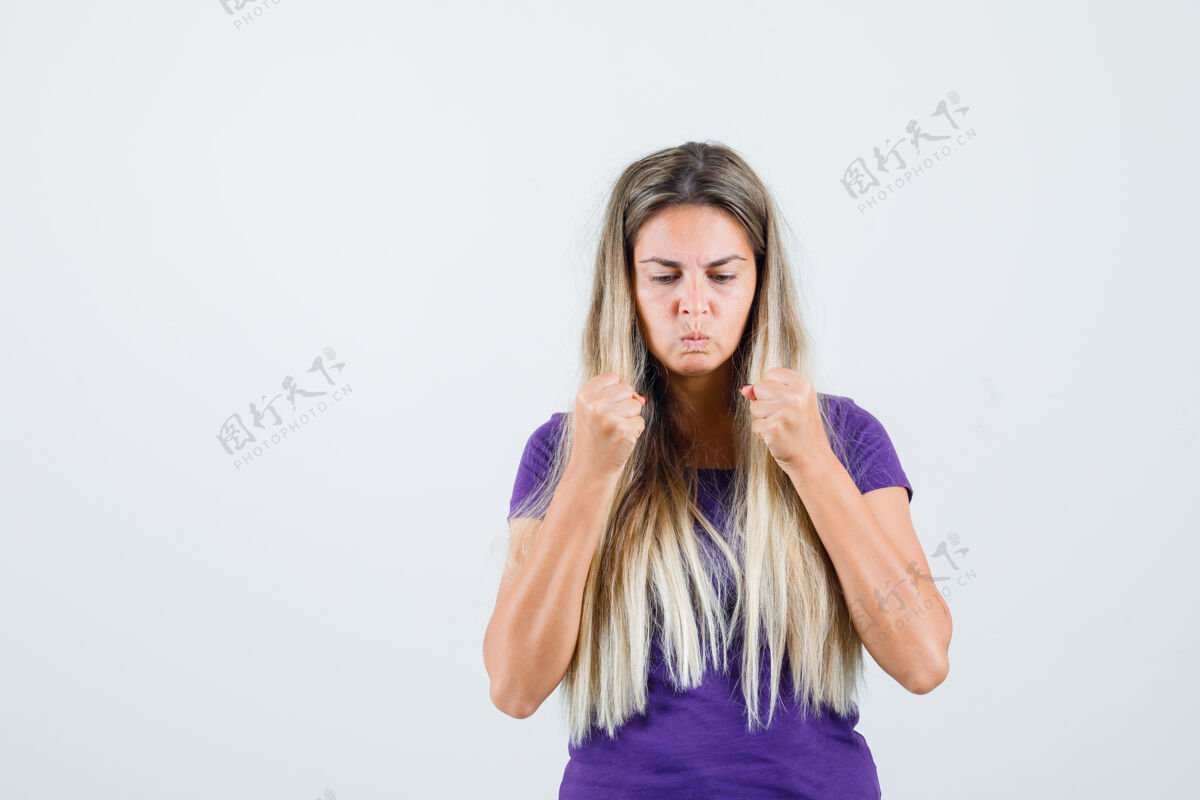 年轻穿着紫罗兰色t恤握紧拳头的年轻女士看起来很强壮正面视图人保持女人