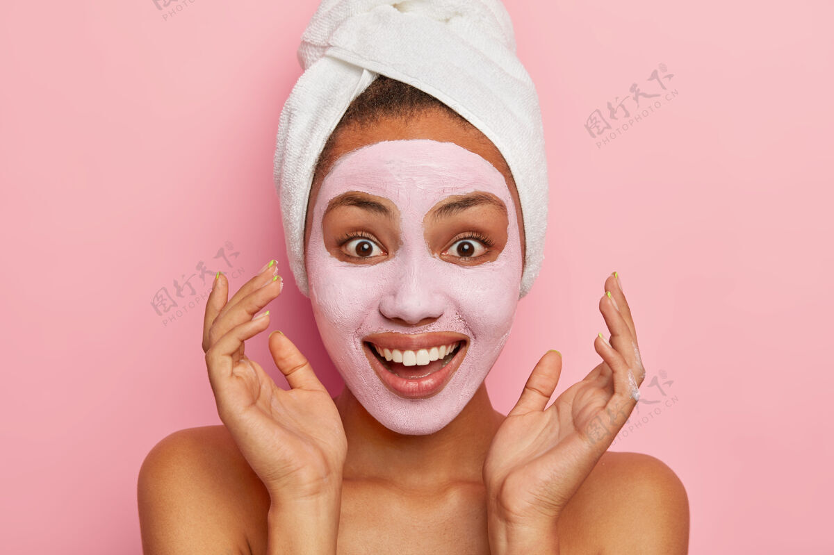 润肤霜乐观的年轻美国黑人女性的头颅紧靠双手 用面罩放松 有着灿烂的微笑外观特写面膜