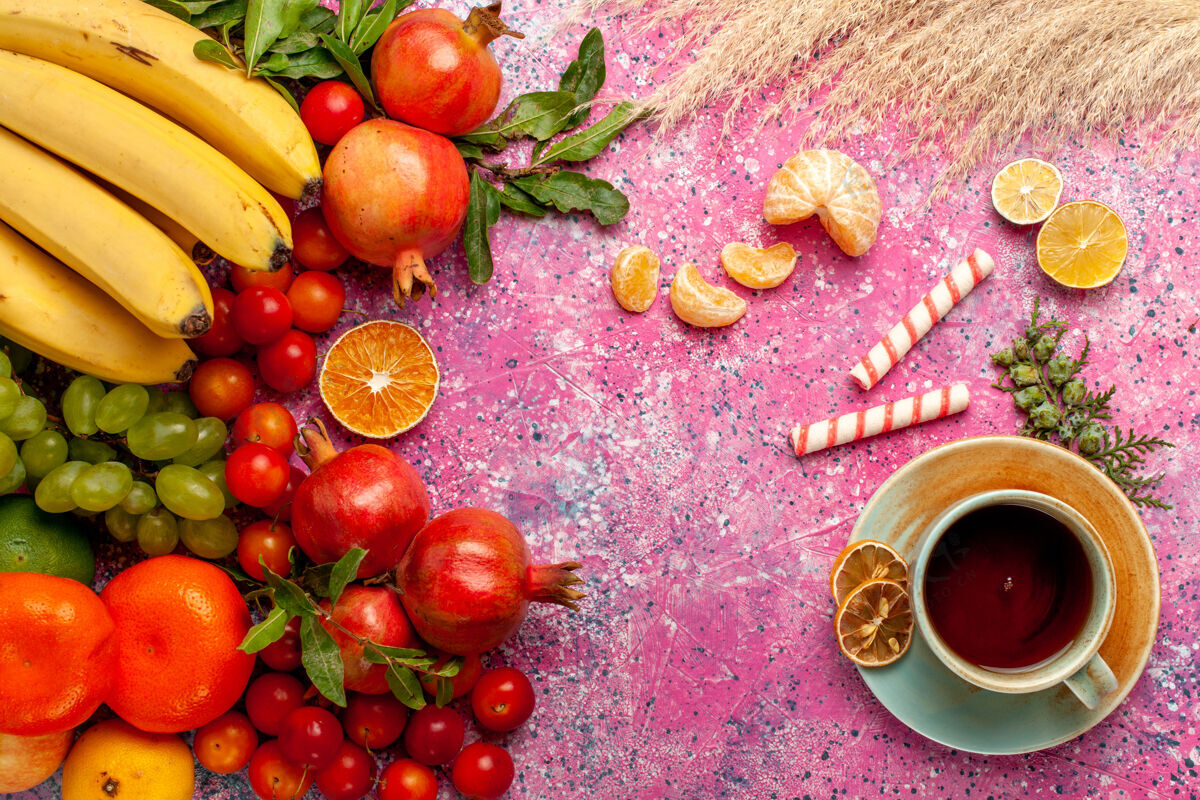 顶级顶视图新鲜水果组成与茶杯浅粉红色的表面生的杯子水果