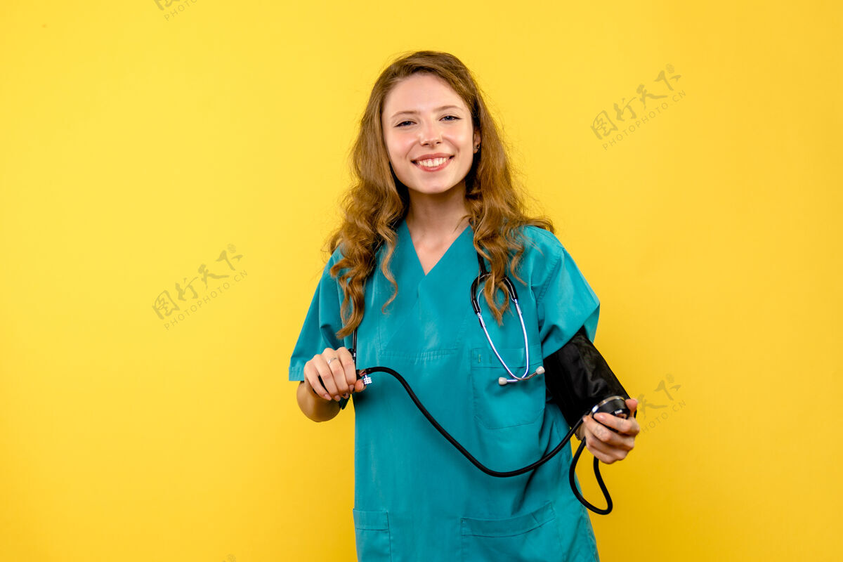 女医生前视图女医生在黄色空间测量压力专业医学听诊器
