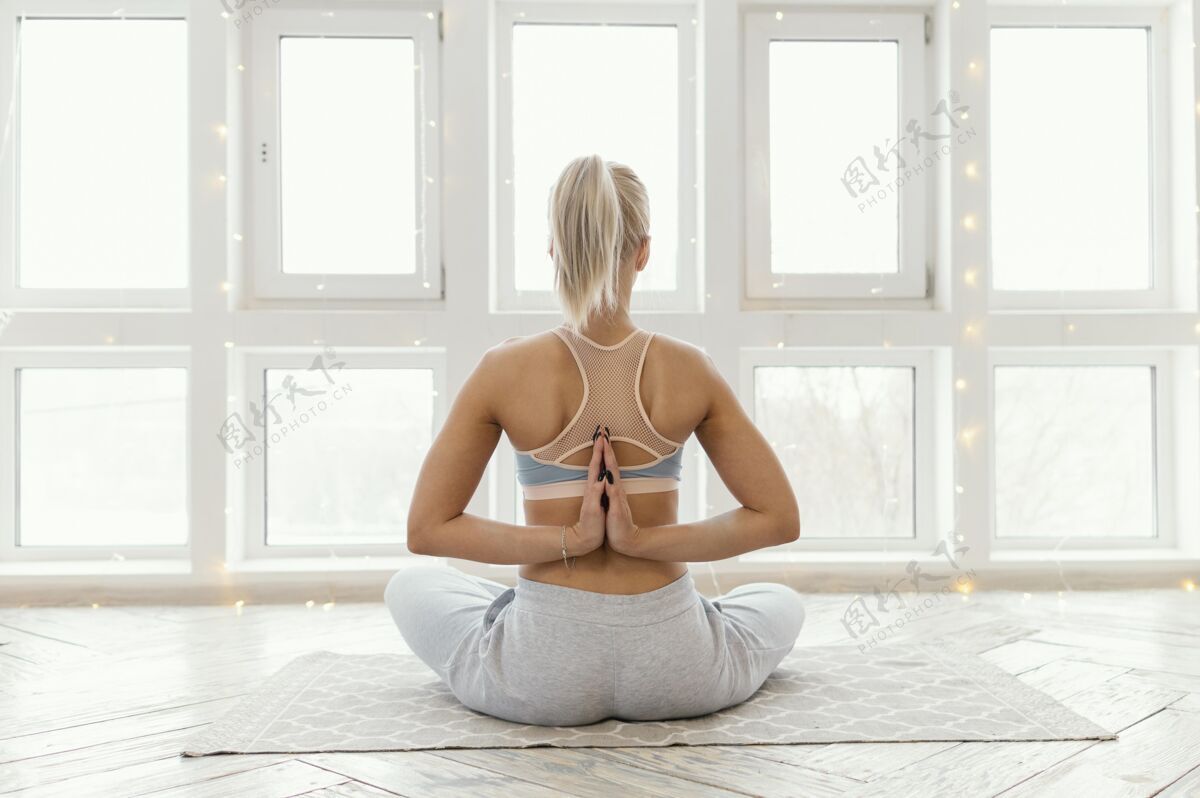 后视图坐在垫子上冥想的女人运动室内瑜伽垫