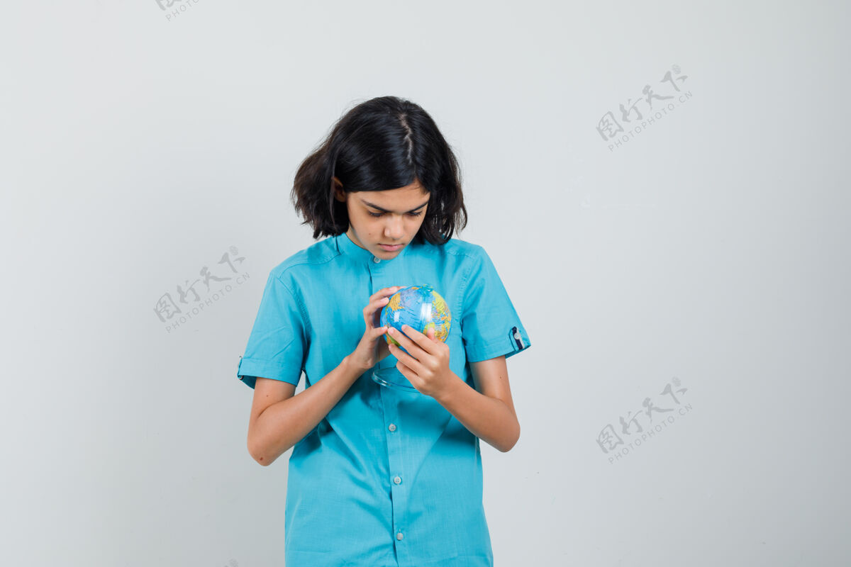 女人年轻女士穿着蓝色衬衫看着迷你地球仪 神情凝神年轻快乐兴奋