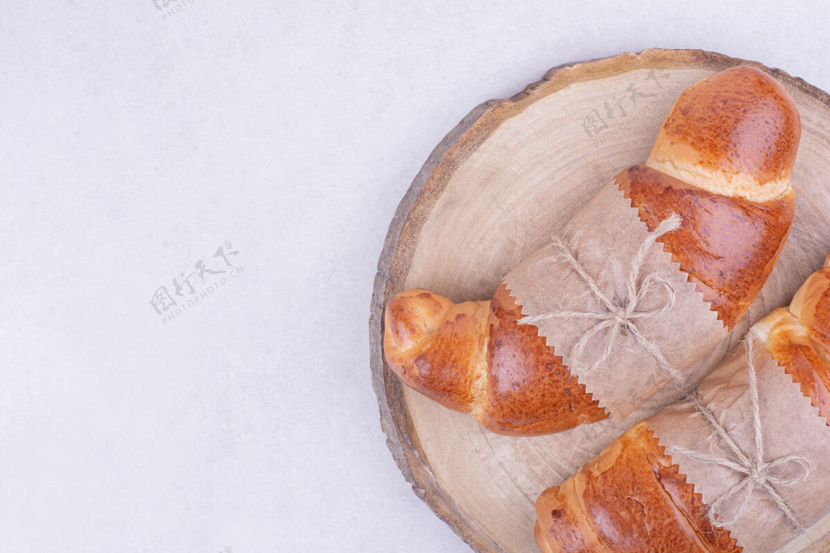 健康羊角面包被隔离在灰色表面的木盘上面包房美味糕点