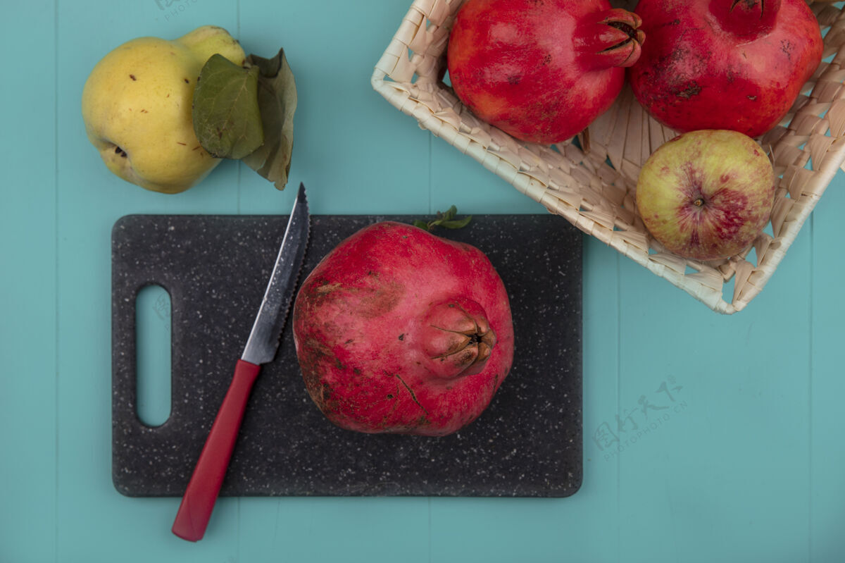 厨房新鲜石榴的俯视图在一个黑色的菜板上 刀子上放着一桶水果 背景是蓝色的视图板新鲜