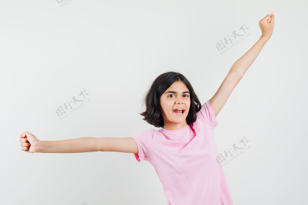 青少年穿着粉色t恤的小女孩展示了成功的姿态 伸展双臂 看起来很开心 正面图青少年美丽人物