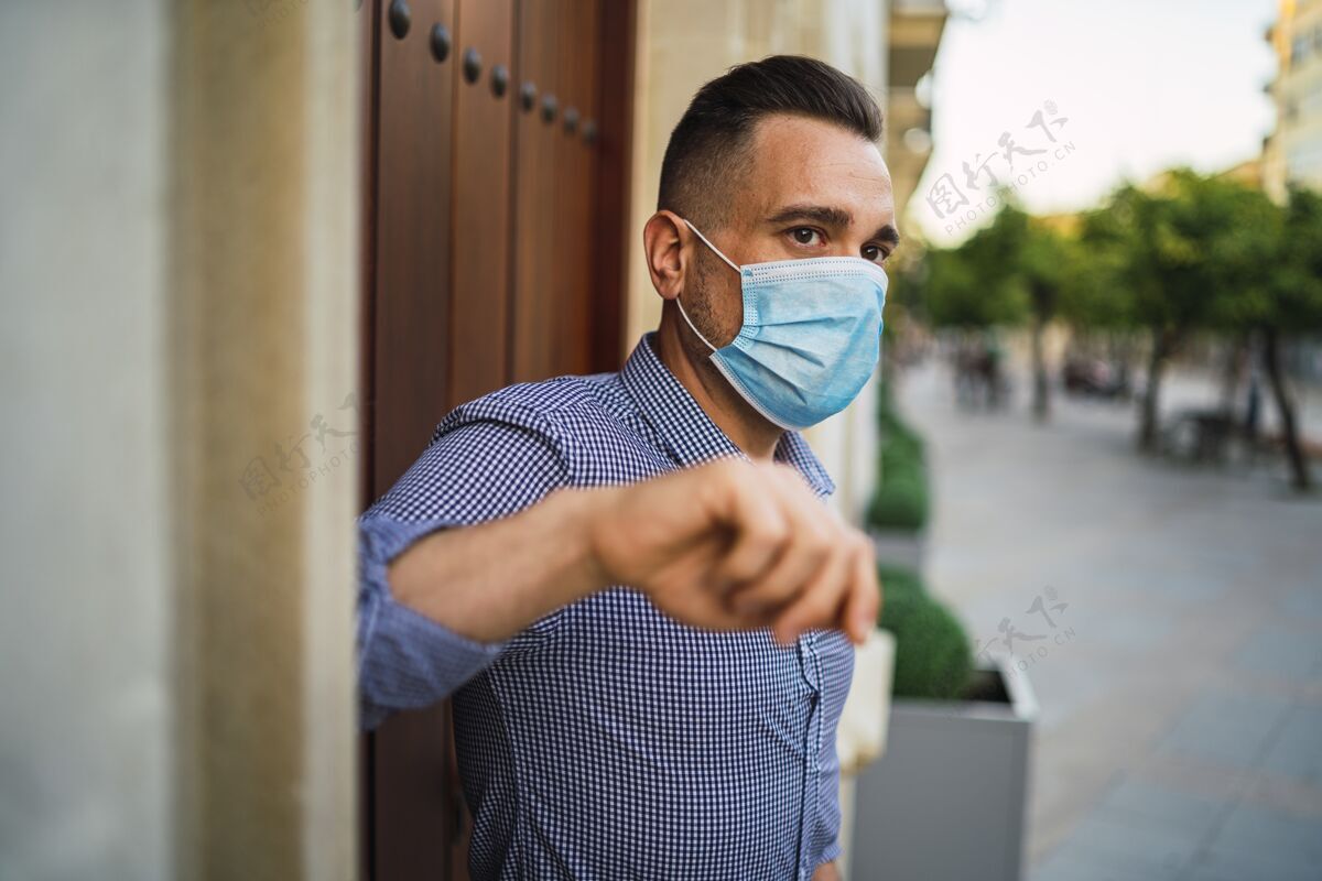 男性身穿蓝色衬衫 戴着医用面罩的年轻男子站在门口男人门健康