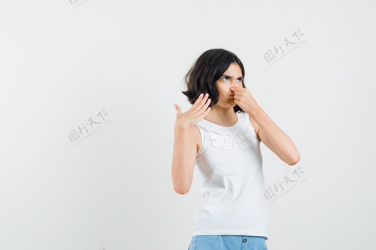 人小女孩穿着白衬衫 短裤捏鼻子 由于臭味和看起来恶心 前视图成人肖像青年
