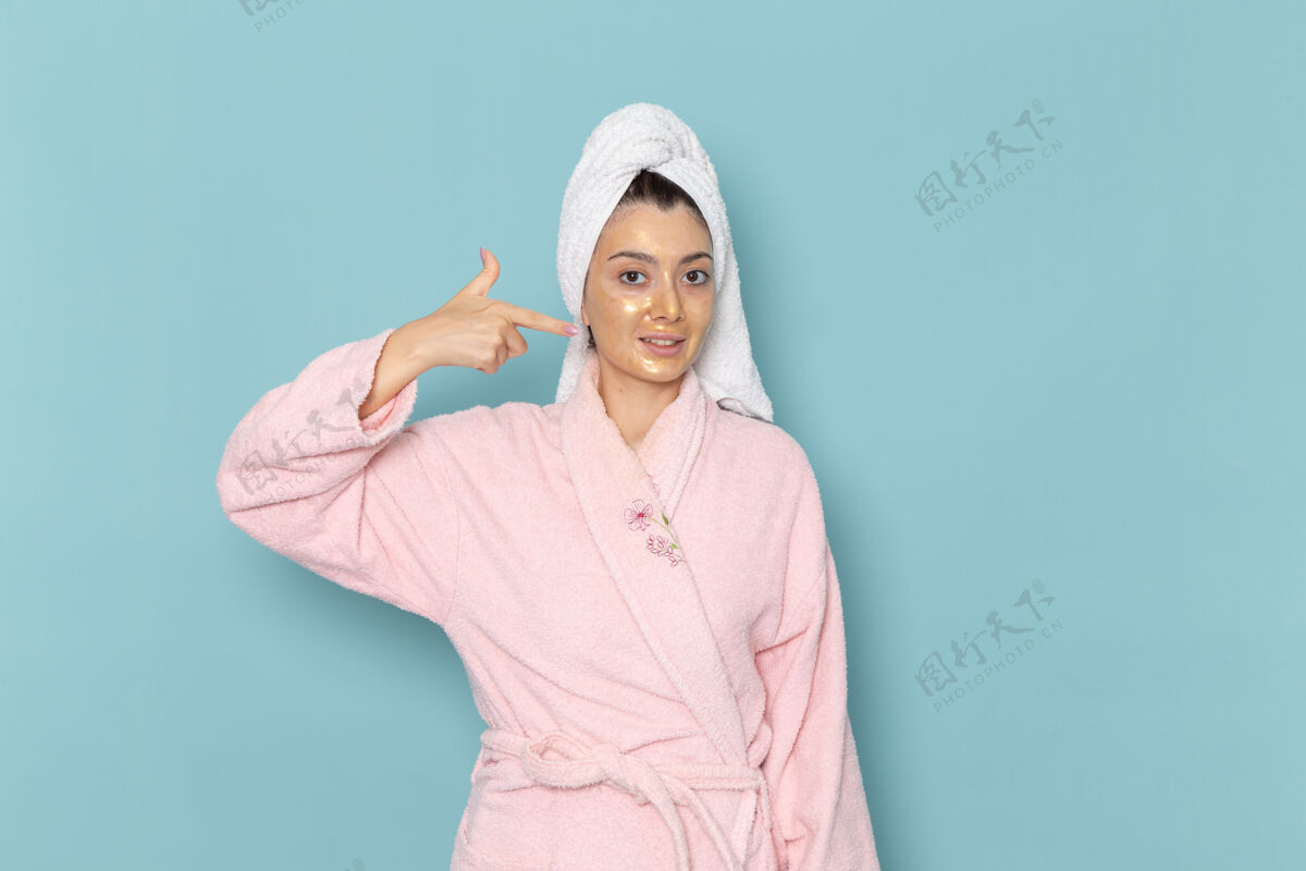 运动衫正面图年轻女性穿着粉色浴袍淋浴后在蓝色墙壁上摆姿势清洁美丽干净的水自我护理霜淋浴衣服视图清洁