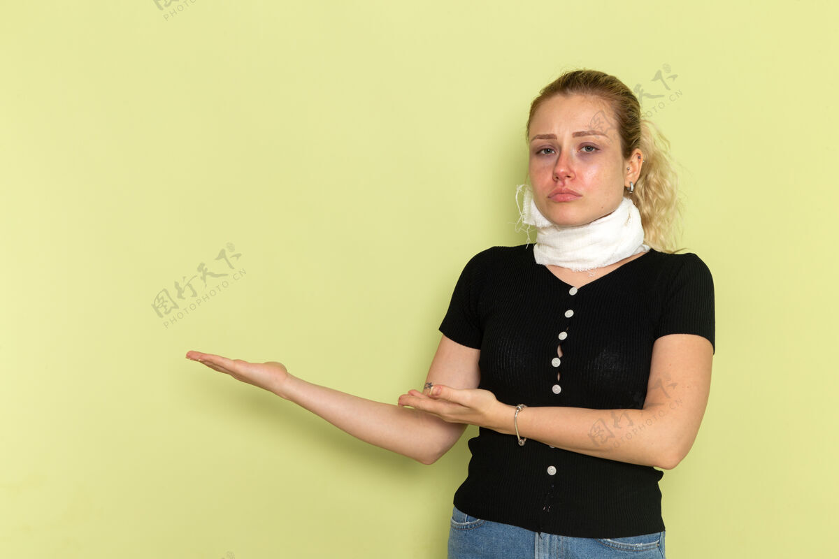 年轻人正面图：年轻女性 脖子上缠着白毛巾 感觉非常不舒服 在浅绿色的办公桌上摆着病态的姿势 女性健康病态病人周围视图