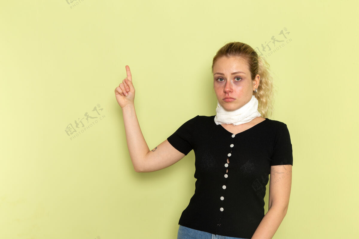 病人正面图年轻女性 脖子上缠着白毛巾 感觉很不舒服 病态地摆在浅绿色的办公桌上 病态的模特儿医药健康病态灯光毛巾书桌