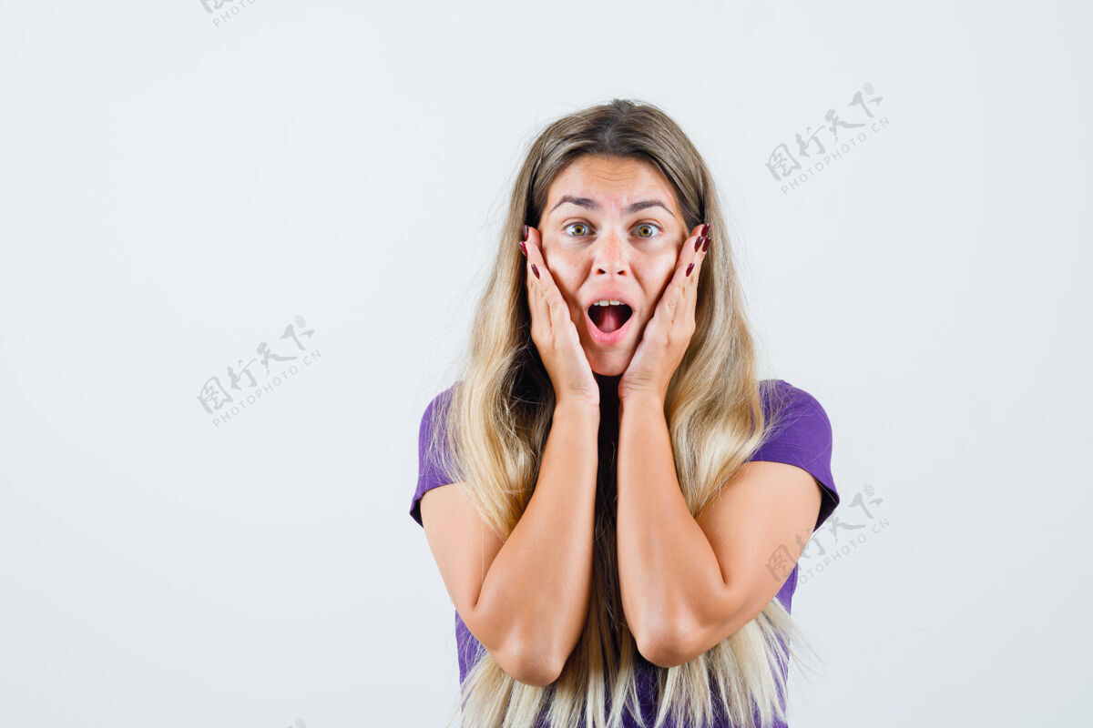 时尚金发碧眼的女士手放在脸颊上穿着紫罗兰色的t恤衫 看起来很惊讶 正面视图紫罗兰时尚女士