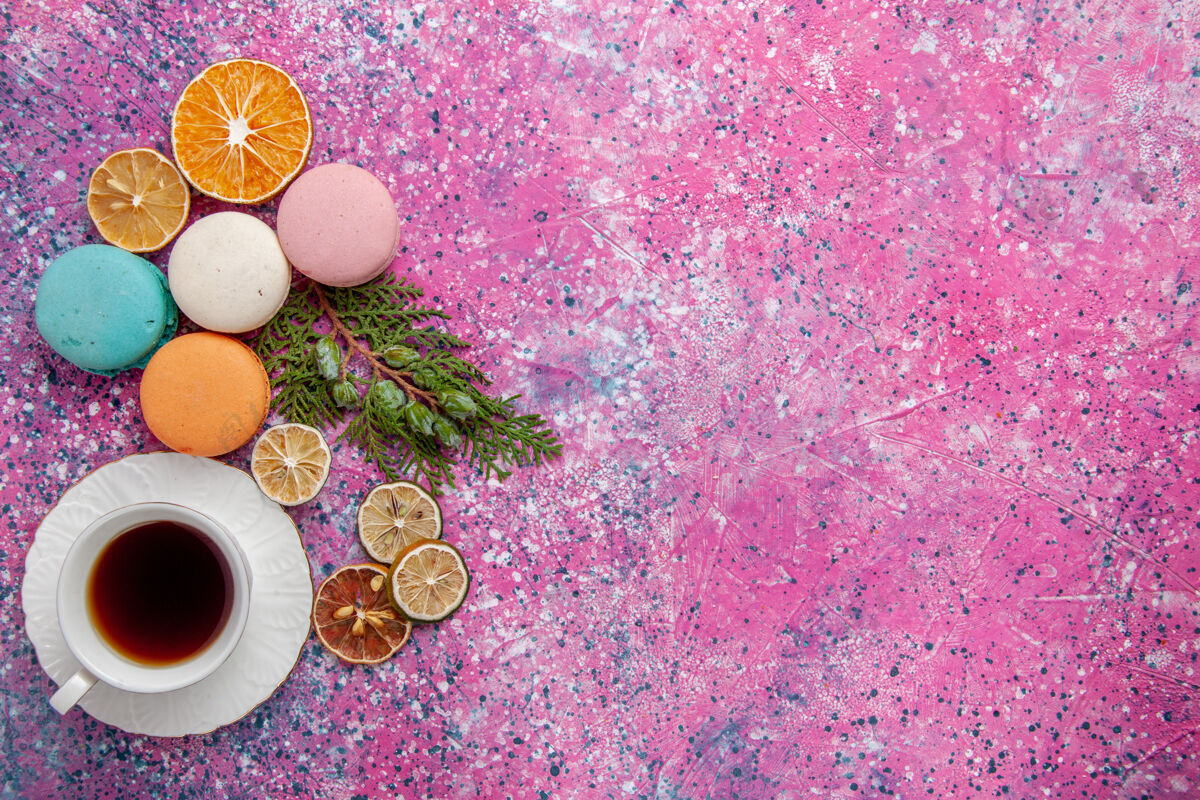 庆典顶视图一杯茶 配上五颜六色的法国马卡龙和华夫饼 粉色蛋糕饼干糖甜饼茶粉末装饰五颜六色