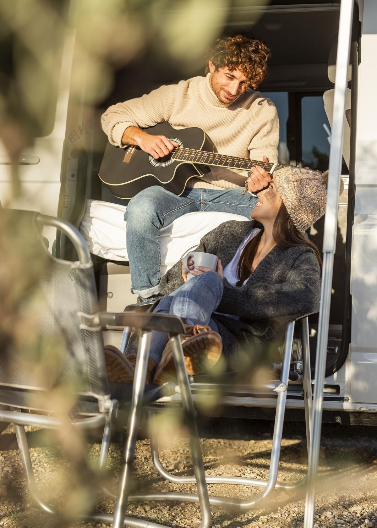 旅行夫妇放松和弹吉他旁边的汽车 而在公路旅行旅行汽车吉他