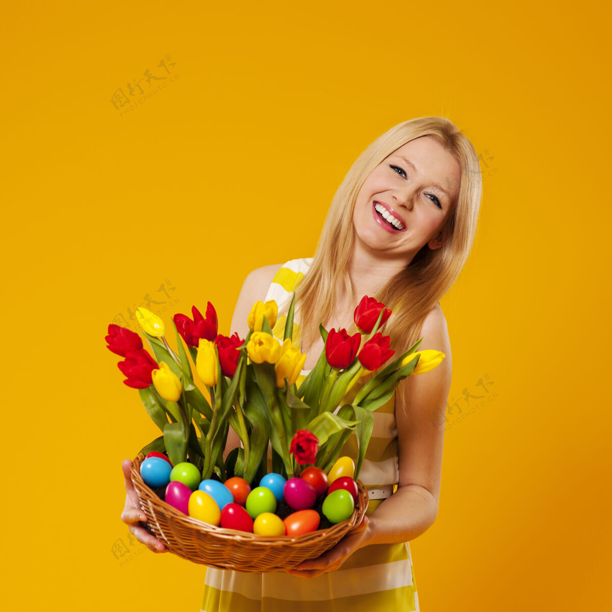 庆祝快乐的女人拿着春花和复活节彩蛋的篮子站立柳条金发