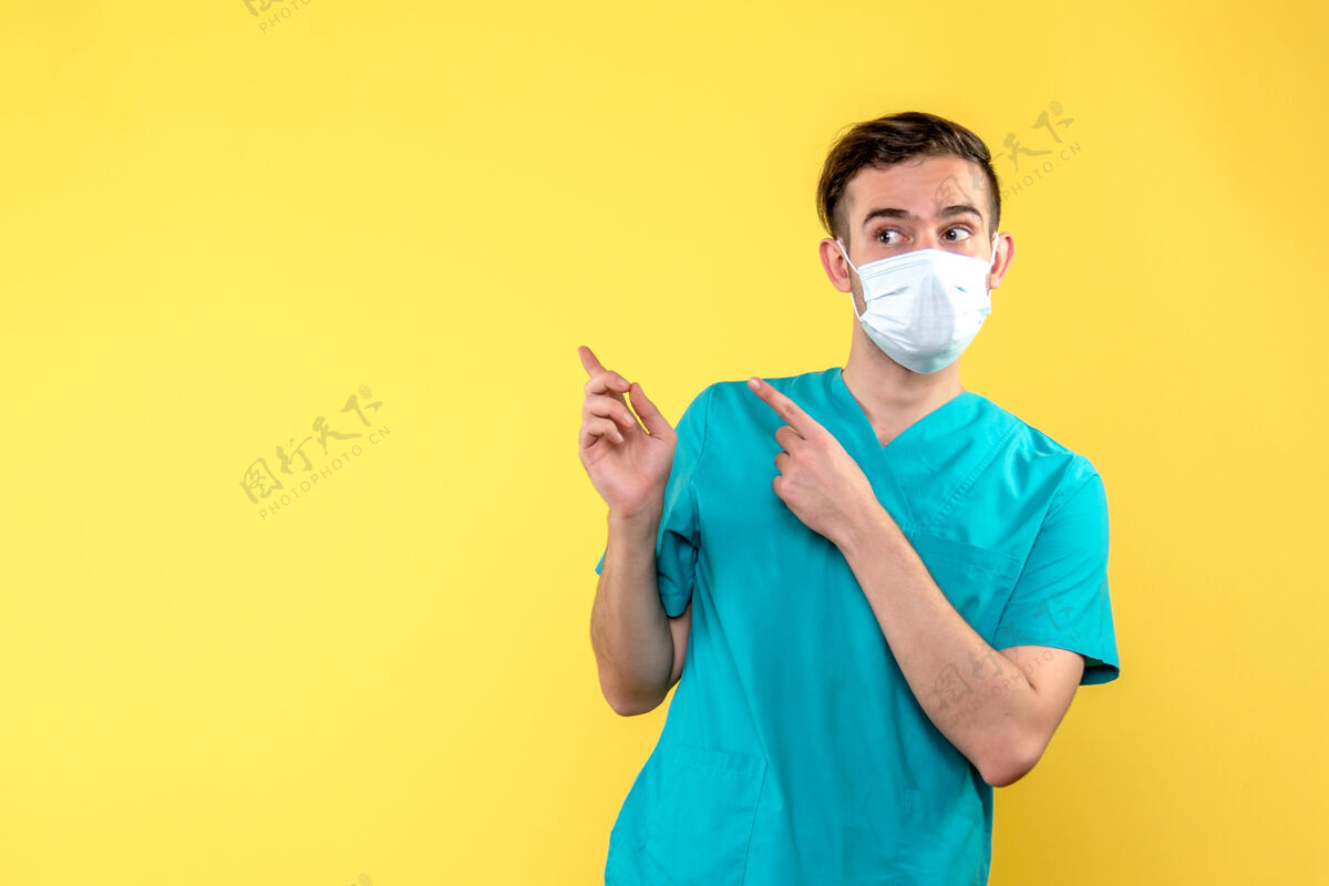 黄色黄色墙上戴着面具的男医生的正视图健康表情人