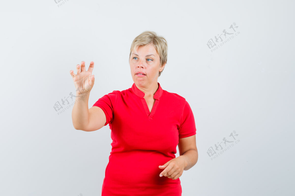 抱着一个成熟的女人穿着红色t恤假装拿着一个小东西 看起来很专注成熟脸女性