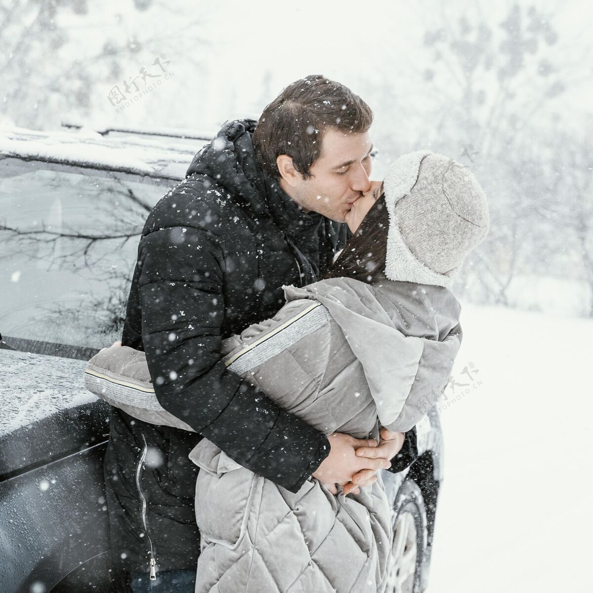 女人一对情侣在雪地里接吻 而在公路旅行的侧视图自然旅行逗留