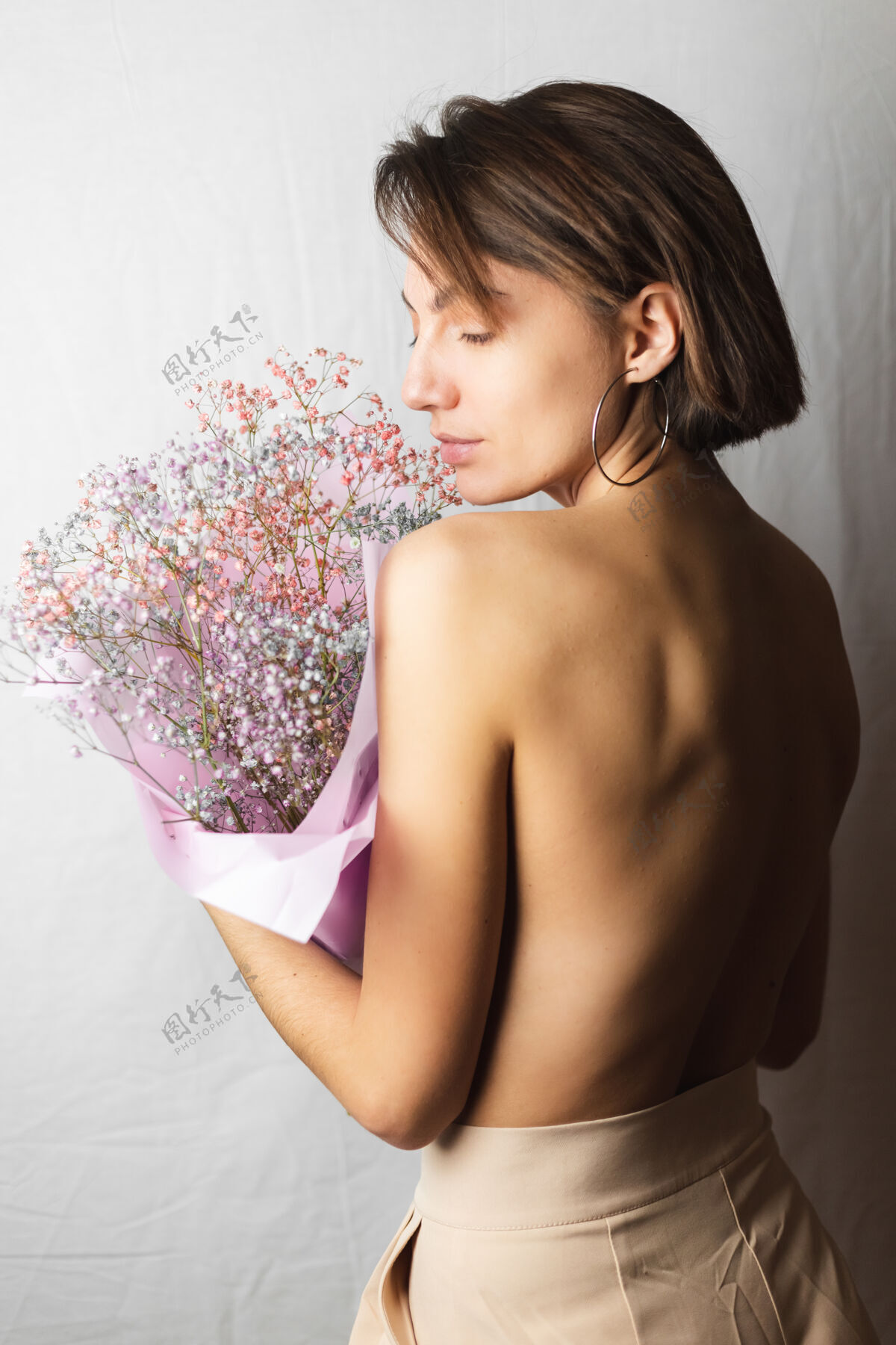 心情一位年轻女子的温柔写照 身穿白色抹布 赤裸上身 手持一束干枯多色的鲜花 微笑可爱 期待春天的到来植物新鲜模特