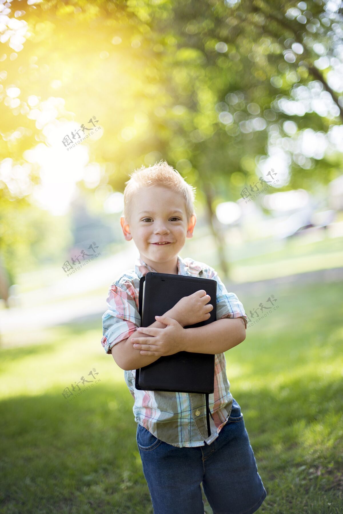 抱着一个孩子拿着圣经对着他的胸膛 同时看着相机的垂直镜头书童年小