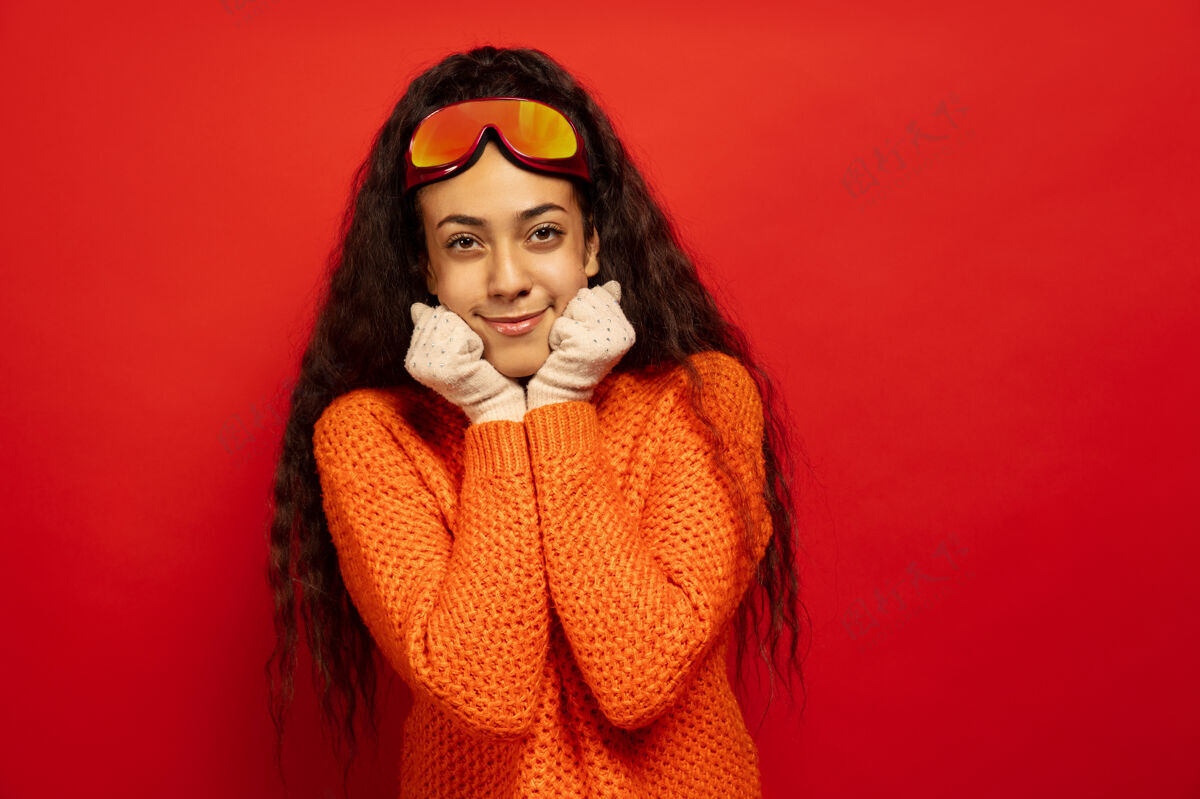 表情以红色工作室为背景 黑色皮肤的非洲裔年轻女子的滑雪面具肖像人类情感的概念 面部表情 销售 广告 冬季运动和假日微笑 看起来很可爱人微笑黑发