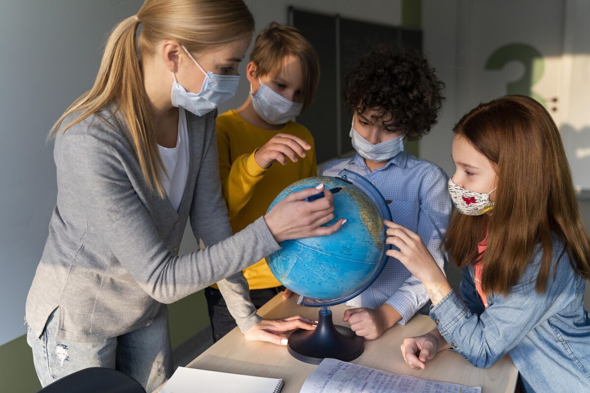 女性带着医学面具的女老师在课堂上用地球仪教地理流行病返校女性