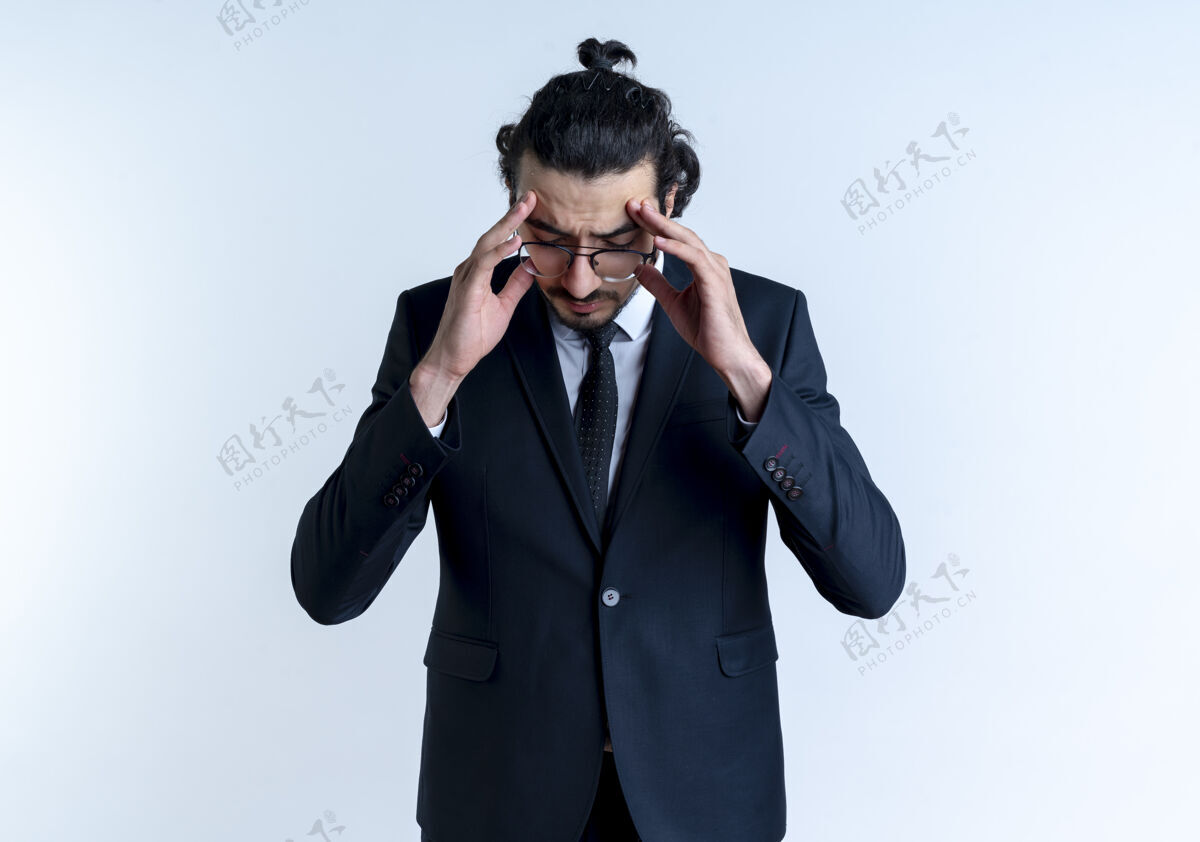 姿势一个穿着黑西装戴着眼镜的商人站在白墙上摸着他头痛的太阳穴眼镜西装男人