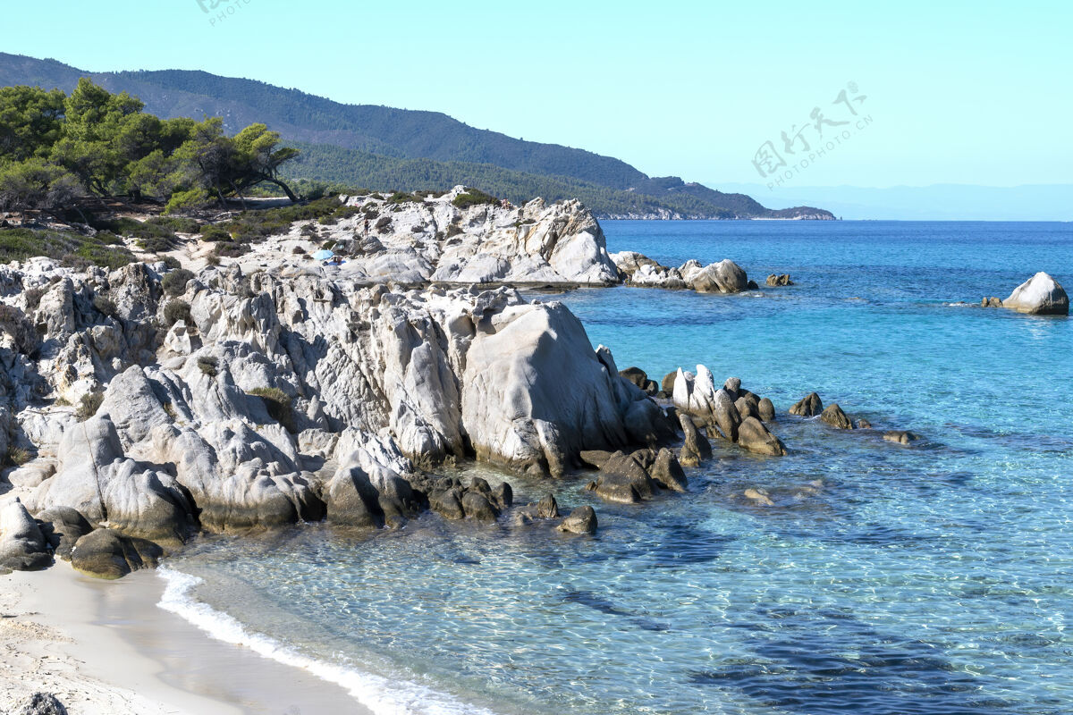 度假村爱琴海海岸周围绿树成荫 岩石和灌木丛 蓝色的海水和休息的人 希腊观点海岸希腊
