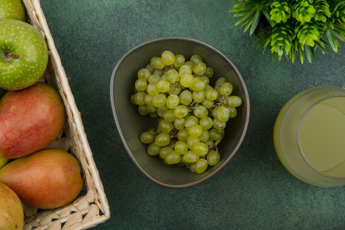 葡萄顶视图绿色的葡萄在一个碗里 绿色的苹果和梨在一个篮子里 果汁在绿色的背景上梨食物视图