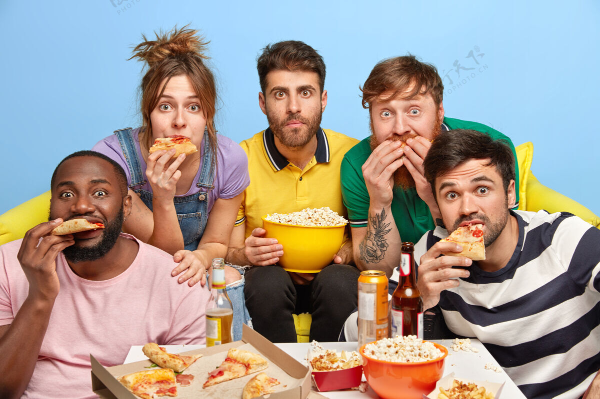 男性最好的朋友在家看电视 享受他们的假期 吃美味的比萨饼和爆米花害怕业余时间汉堡