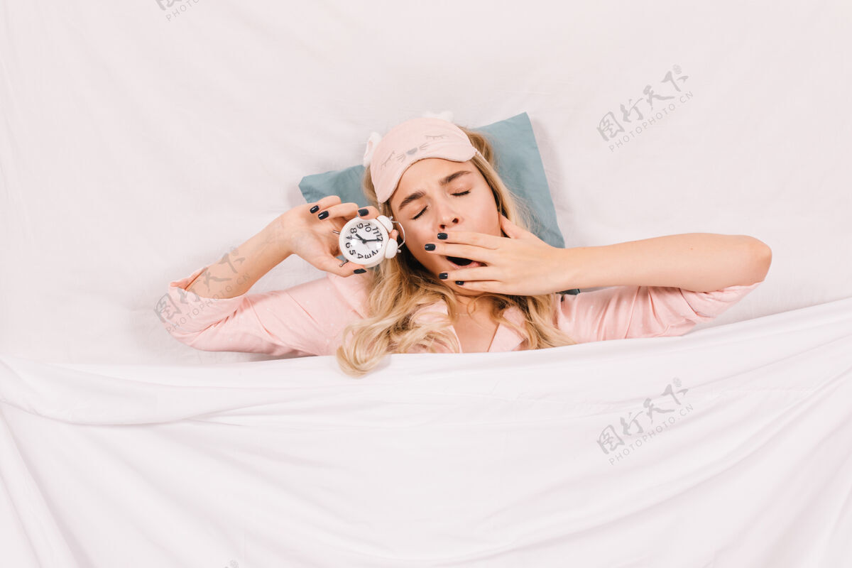 时尚睡觉的女人在床上打哈欠的俯视图室内年轻女人