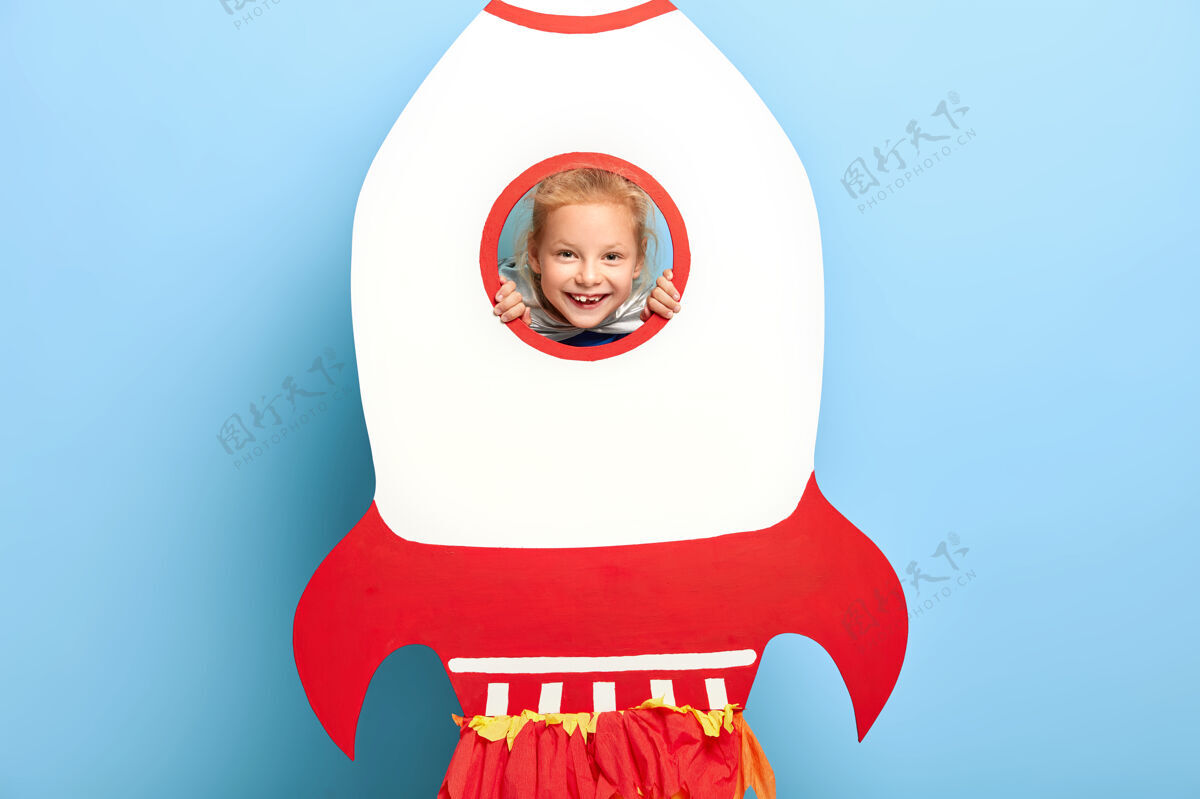 高兴可爱的孩子在大纸火箭后面摆姿势童年满意欢乐