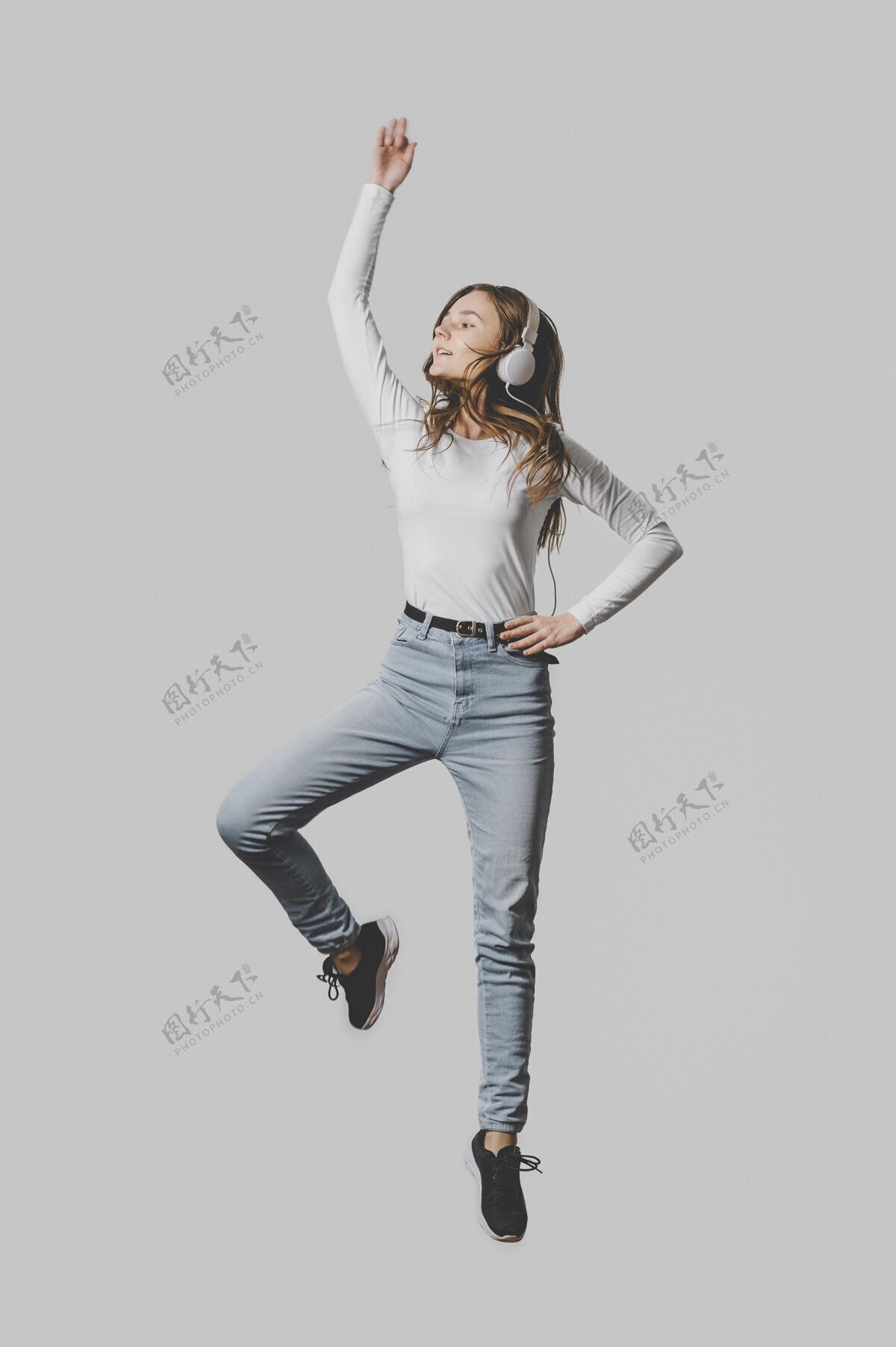 女性戴着耳机在空中跳跃的女人的前视图人类个人快乐